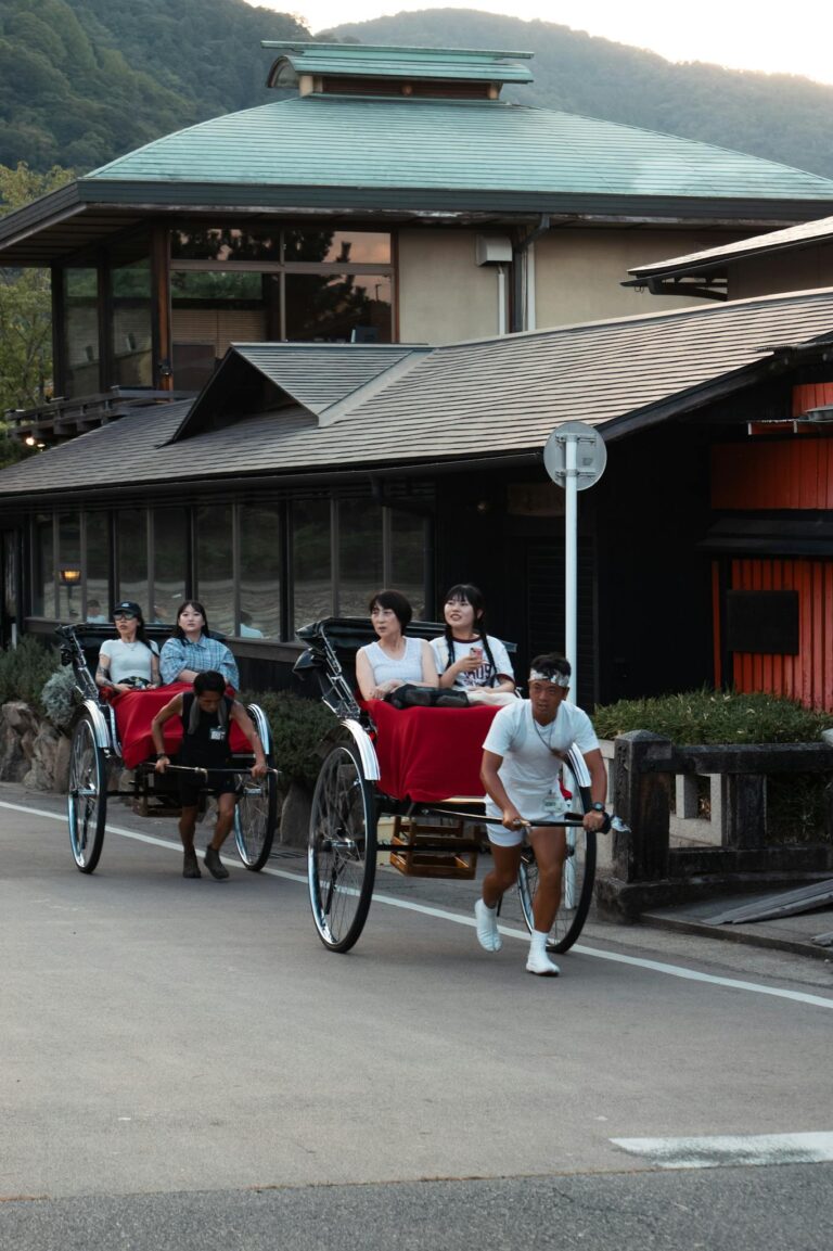 Men pulling rickshaws with passengers in the bustling streets of Kyoto, Japan.